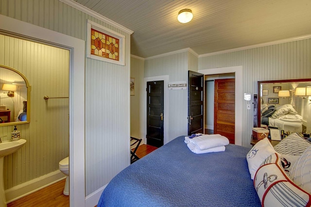 bedroom featuring baseboards, ornamental molding, wood finished floors, and a closet