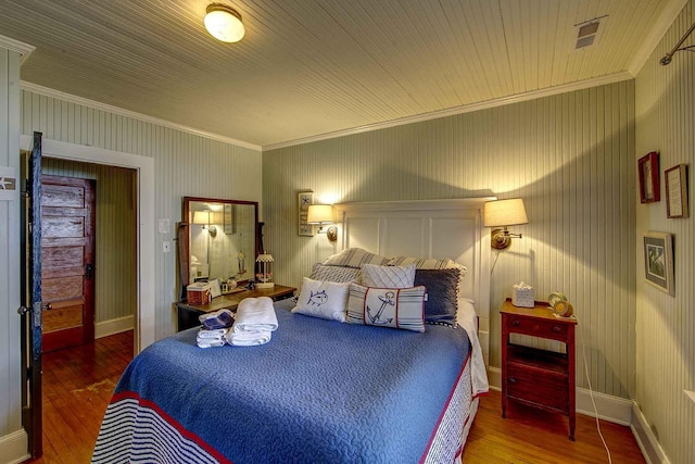 bedroom with wood-type flooring, crown molding, and baseboards