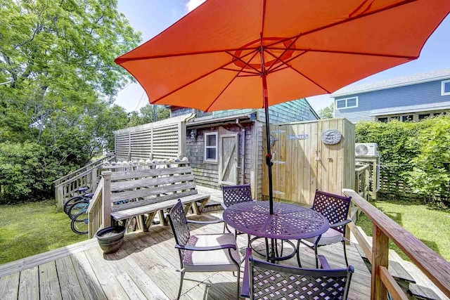 deck featuring outdoor dining area, an outdoor structure, and a yard