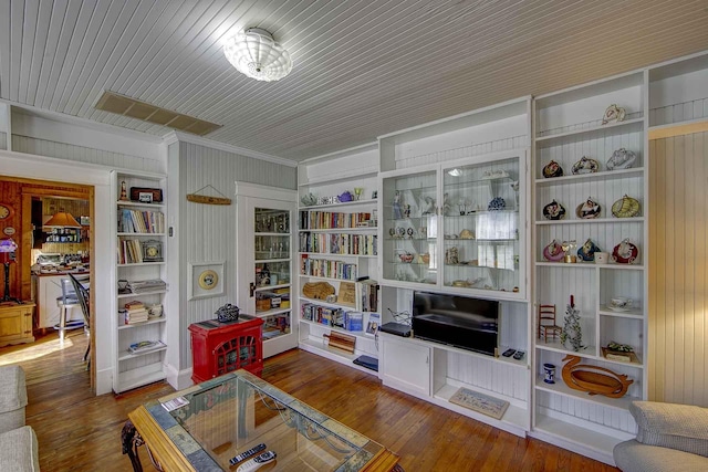sitting room featuring crown molding, wood walls, and wood finished floors