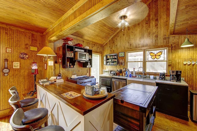 kitchen featuring wood ceiling, wood finished floors, a sink, wooden walls, and stainless steel appliances