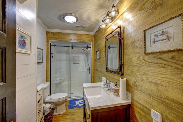 bathroom featuring vanity, ornamental molding, wood finished floors, toilet, and a stall shower