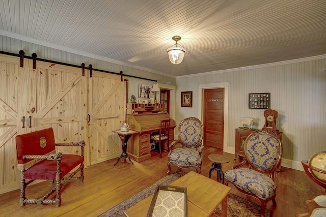 sitting room featuring wood-type flooring, crown molding, and a barn door