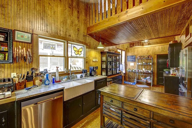 kitchen featuring wood walls, beamed ceiling, wooden ceiling, a sink, and appliances with stainless steel finishes