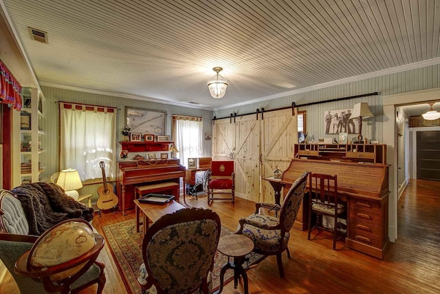 interior space featuring wood-type flooring, a barn door, visible vents, and ornamental molding