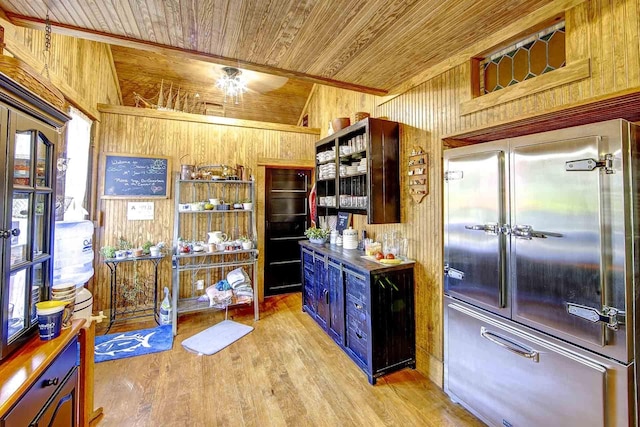 kitchen with built in refrigerator, wood walls, wooden ceiling, and light wood-style floors