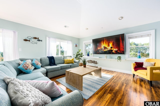 living room with visible vents, vaulted ceiling, and wood finished floors