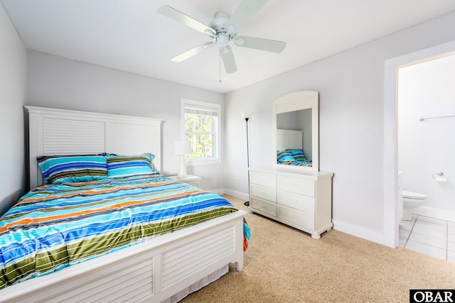 bedroom featuring baseboards, ensuite bathroom, a ceiling fan, and light colored carpet