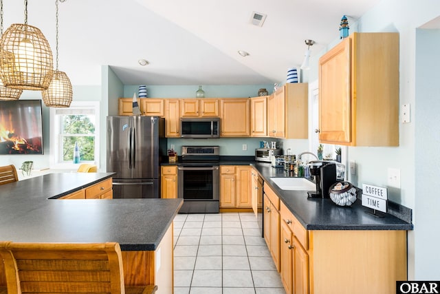 kitchen with appliances with stainless steel finishes, dark countertops, light brown cabinetry, and a sink