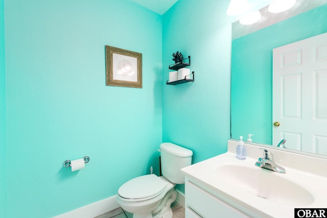 half bathroom featuring toilet, vanity, and baseboards