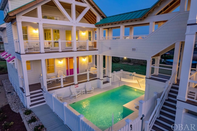 back of property featuring a fenced in pool, a patio, metal roof, a balcony, and a fenced backyard