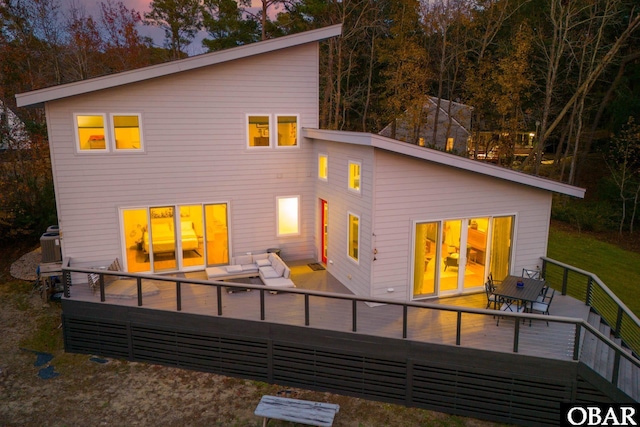 back of house at dusk featuring an outdoor hangout area and a wooden deck