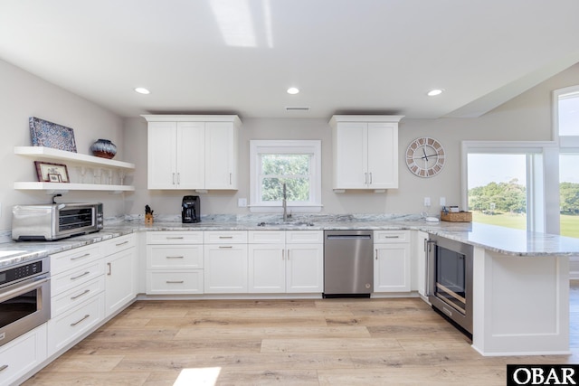 kitchen featuring stainless steel appliances, white cabinets, a sink, and a peninsula