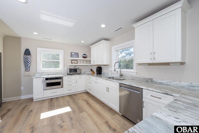 kitchen with light stone counters, visible vents, appliances with stainless steel finishes, light wood-style floors, and a sink