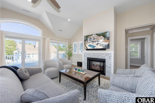 living room with plenty of natural light, visible vents, vaulted ceiling, and a tile fireplace