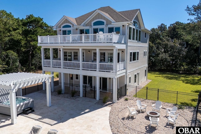 back of house featuring a balcony, a yard, a pergola, a patio area, and a hot tub