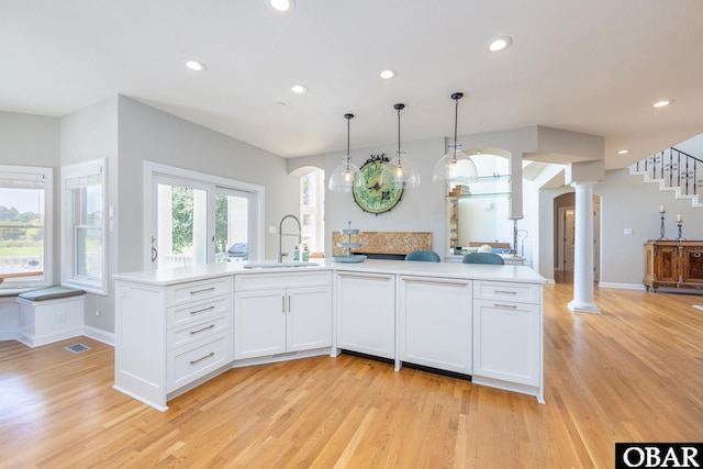 kitchen featuring light countertops, a sink, decorative columns, and white cabinetry