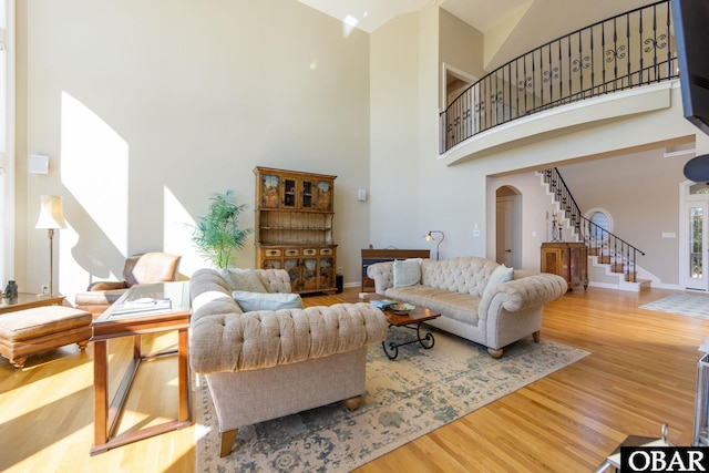 living room with arched walkways, wood finished floors, stairs, and baseboards