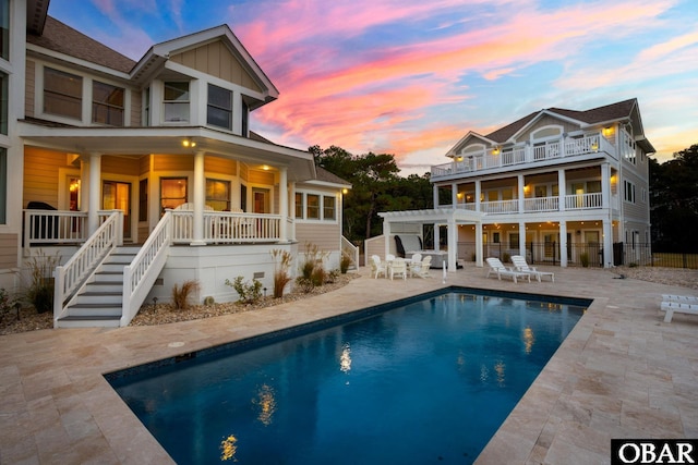 rear view of house featuring board and batten siding, a patio area, fence, an outdoor pool, and stairs