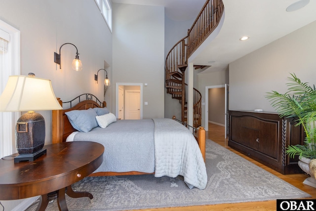 bedroom featuring a high ceiling, wood finished floors, and recessed lighting