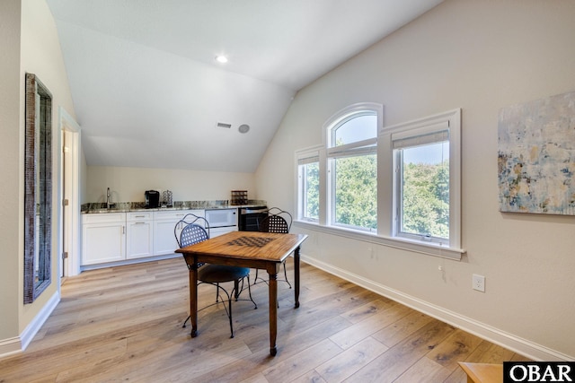 home office featuring visible vents, vaulted ceiling, light wood-style flooring, and baseboards