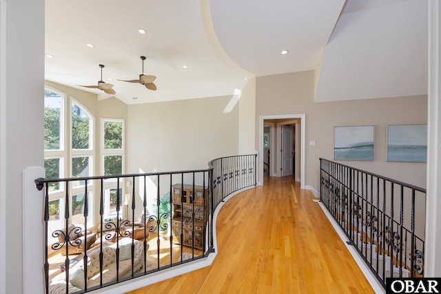 corridor with baseboards, lofted ceiling, wood finished floors, an upstairs landing, and recessed lighting