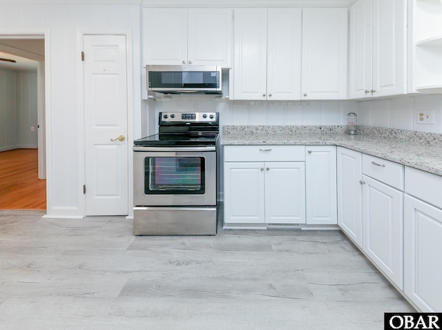 202 Winfall Blvd, Hertford, NC 27944 - kitchen with stainless steel appliances, light wood-style flooring, open shelves, white cabinetry, and light stone countertops