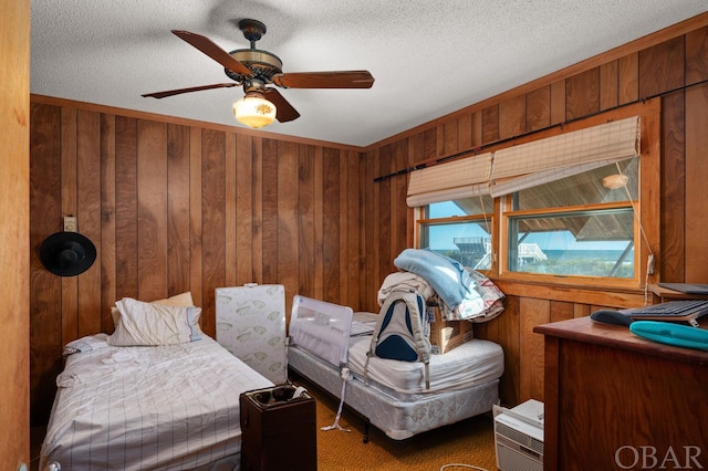 bedroom with wood walls, ceiling fan, and a textured ceiling