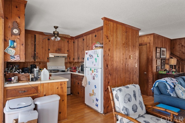 kitchen with brown cabinets, light countertops, white appliances, a peninsula, and under cabinet range hood