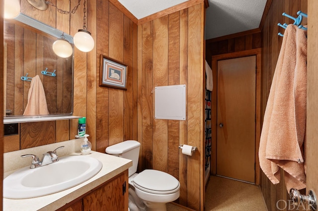 half bathroom featuring toilet, wood walls, and vanity