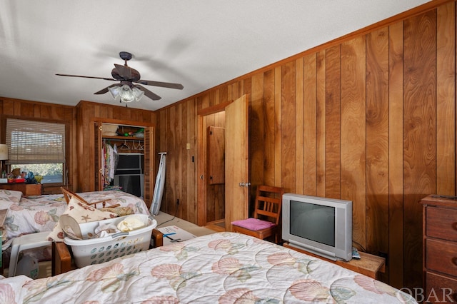 bedroom with ceiling fan, wood walls, and a closet