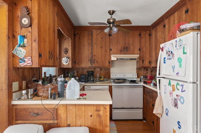 kitchen featuring ceiling fan, under cabinet range hood, white appliances, light countertops, and brown cabinetry