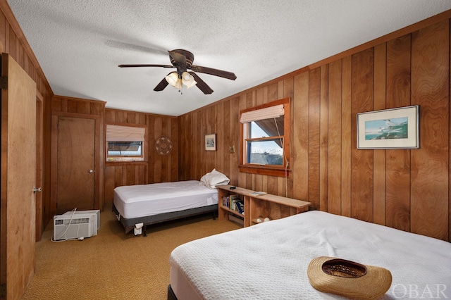 bedroom featuring light colored carpet, ceiling fan, a wall mounted air conditioner, a textured ceiling, and wood walls