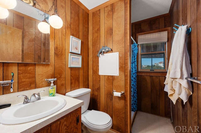 bathroom with wooden walls, toilet, and vanity