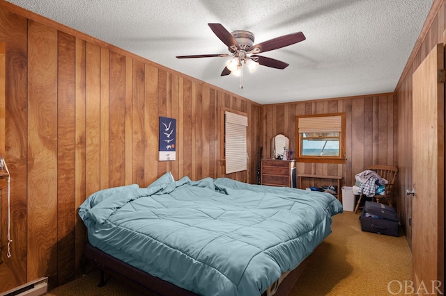 carpeted bedroom with a ceiling fan, wood walls, a textured ceiling, and baseboard heating