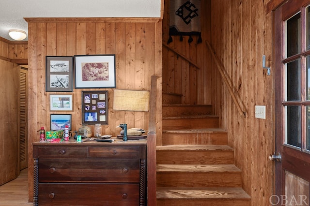 stairway with wooden walls and wood finished floors