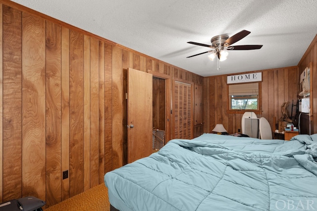 bedroom with a textured ceiling, a ceiling fan, and wooden walls