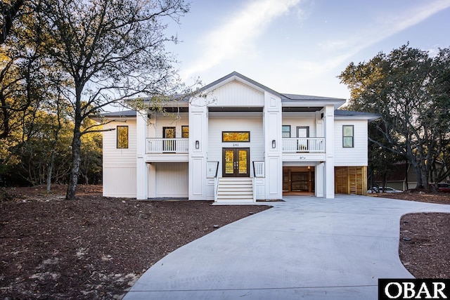 view of front of property with a garage, driveway, french doors, and a balcony