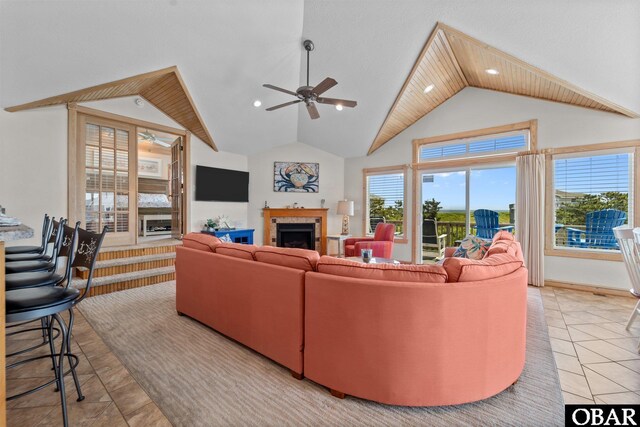 living area with a wealth of natural light, a fireplace, a ceiling fan, and lofted ceiling