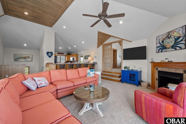 living area featuring carpet floors, a ceiling fan, vaulted ceiling, and a tile fireplace