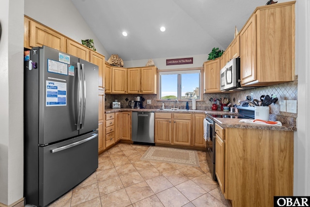 kitchen with light brown cabinetry, appliances with stainless steel finishes, a sink, lofted ceiling, and backsplash