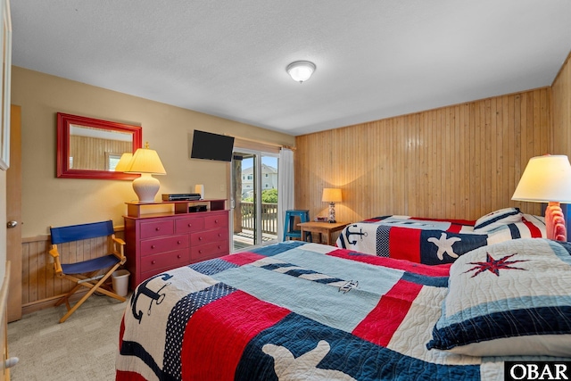 bedroom with carpet floors, wood walls, and access to exterior