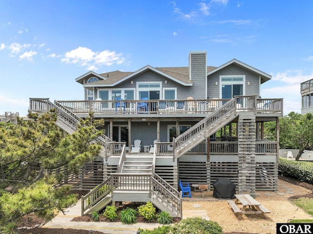 back of house with a deck, a chimney, and stairs