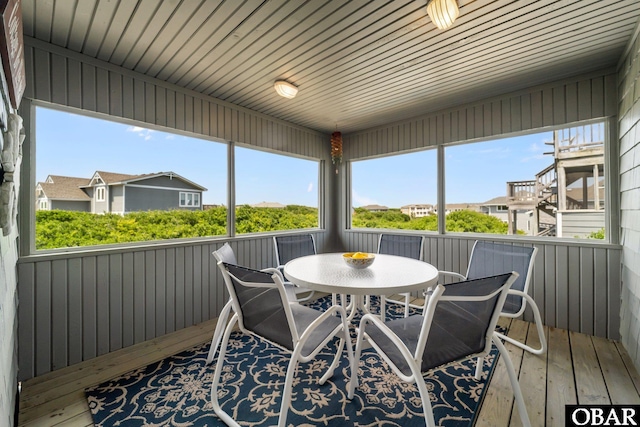 sunroom featuring plenty of natural light, a residential view, and outdoor dining area