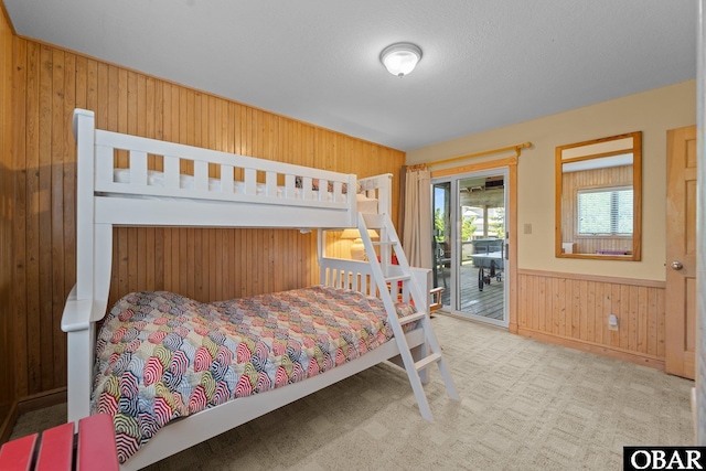 bedroom featuring wooden walls, access to exterior, carpet, and a wainscoted wall