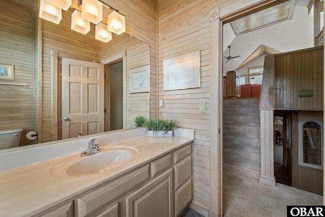 bathroom featuring a ceiling fan, wood walls, vaulted ceiling, and vanity