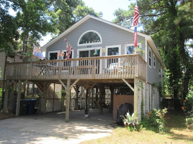 rear view of property with a carport, a wooden deck, and driveway