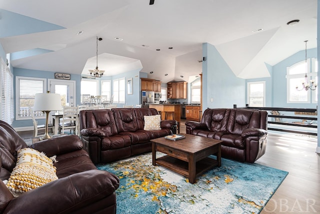 living area with plenty of natural light, vaulted ceiling, and a notable chandelier