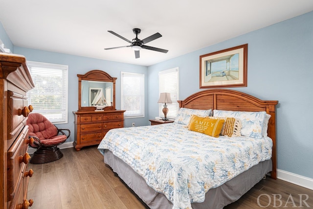 bedroom with ceiling fan, wood finished floors, and baseboards