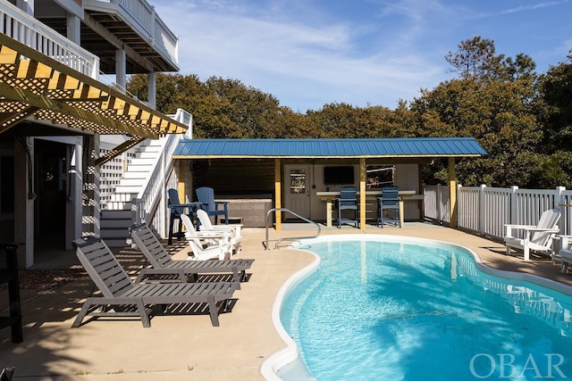 view of swimming pool featuring a fenced in pool, a patio, outdoor dry bar, stairway, and fence